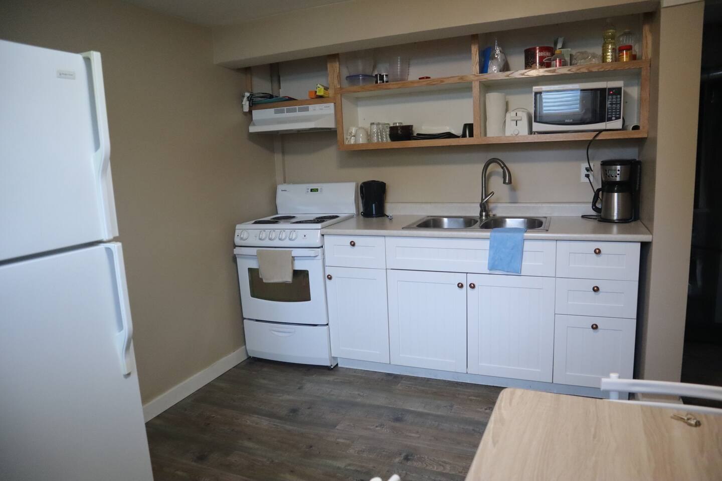 Kitchen with refrigerator, stove, sink and dining table at the basement suite